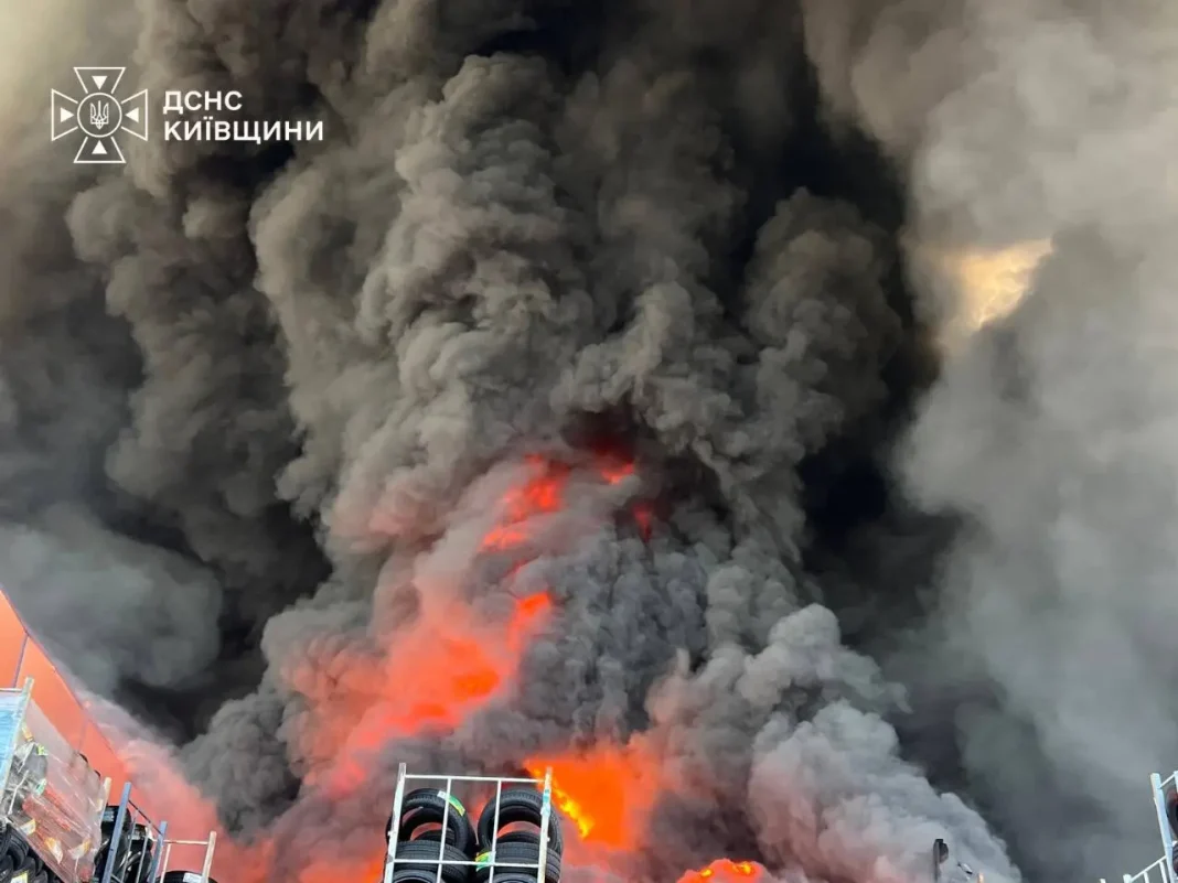 Масштабна пожежа після російського удару по селу Мила на Київщині. Над місцем влучання здіймаються густі клуби чорного диму та видно відкрите полум'я.