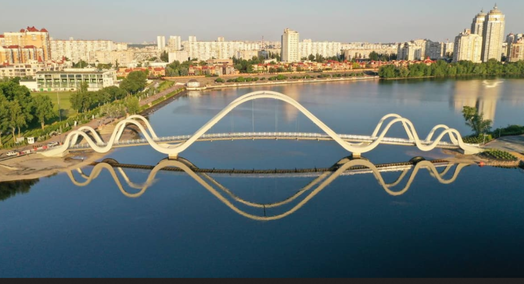 Панорамний вид Києва з хвилястим пішохідним мостом над Дніпром