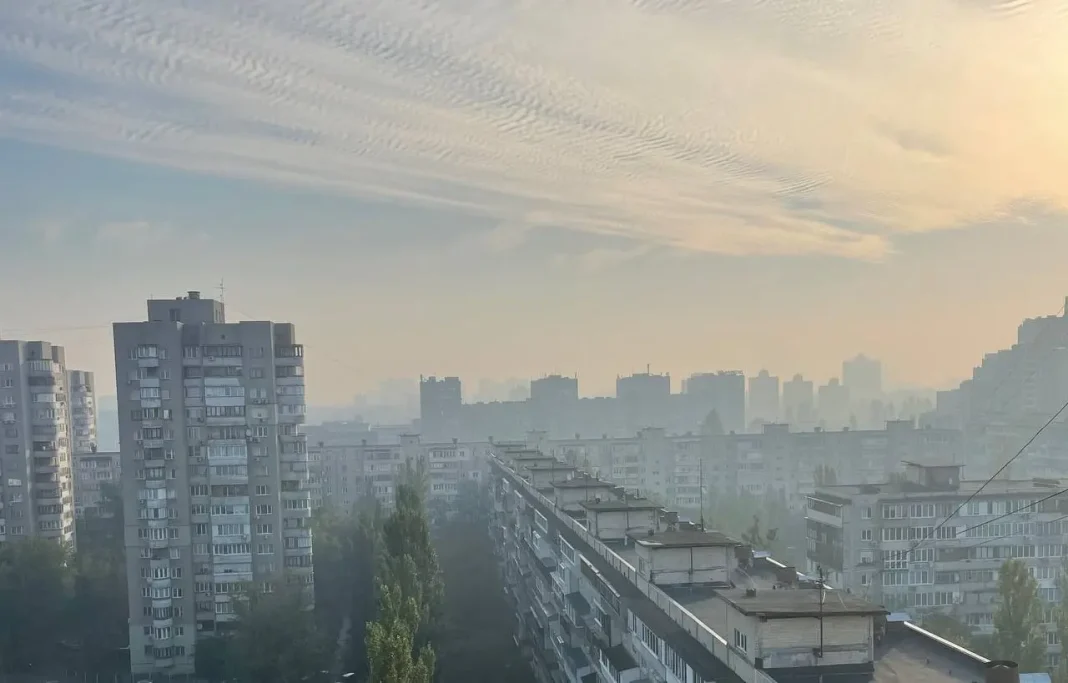 Панорама Києва із серпанком забрудненого повітря над житловими районами на світанку.