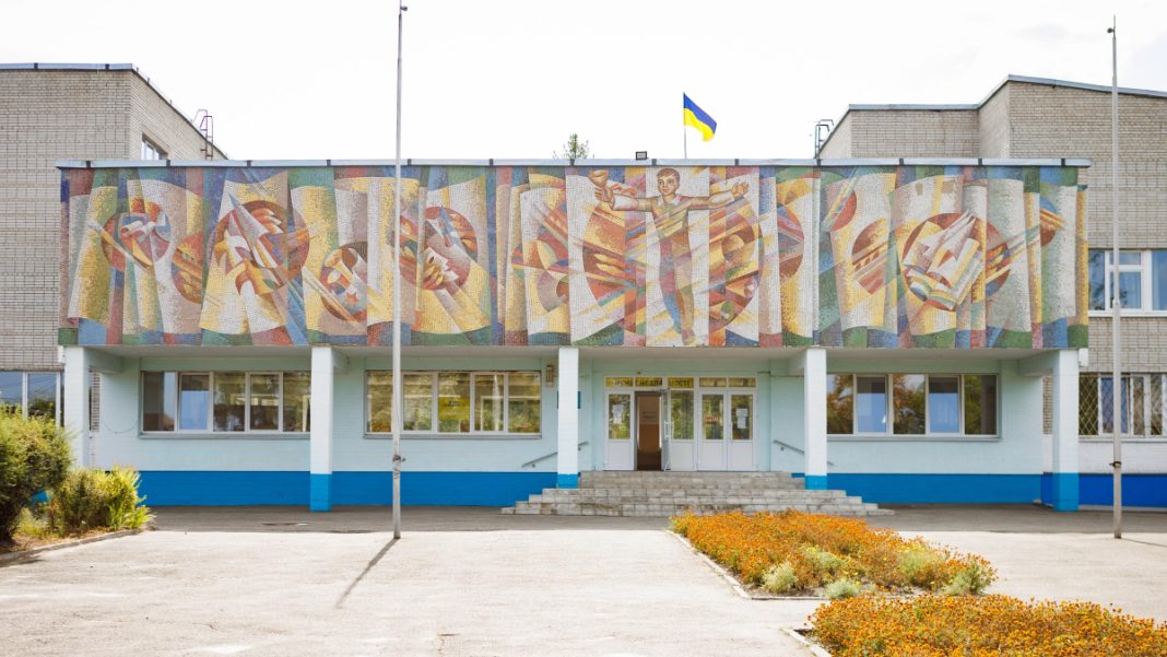 Фасад ліцею з великою українською мозаїкою та державним прапором